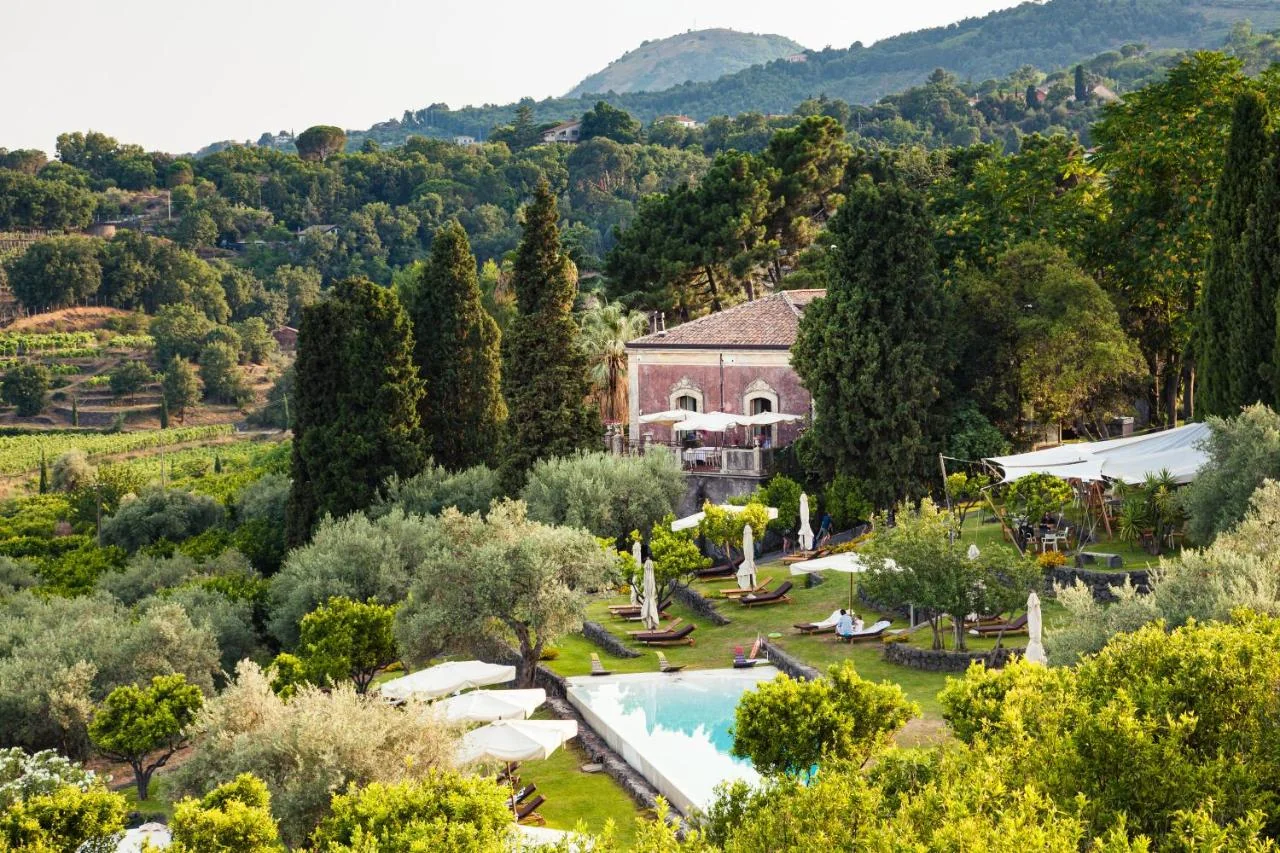 Pink villa surrounded by vineyards and olive groves at Monaci delle Terre Nere on the slopes of Mount Etna